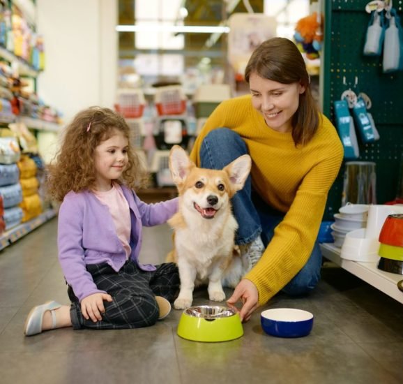 happy-mother-and-daughter-feeding-their-dog-at-pet-shop-1536x922